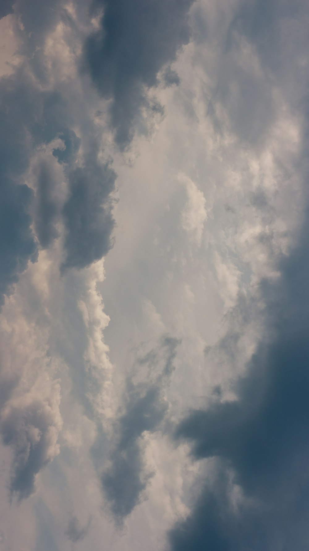 a plane flying through a cloudy blue sky