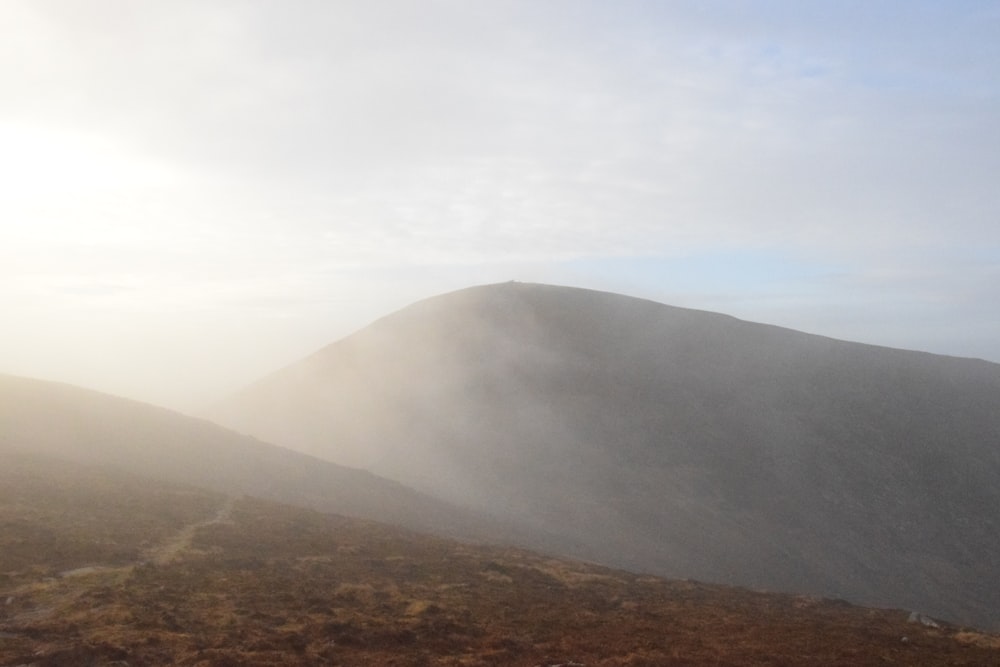 a hill covered in fog and mist on a cloudy day