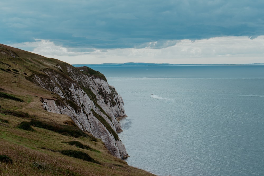 a boat is on the water near a cliff