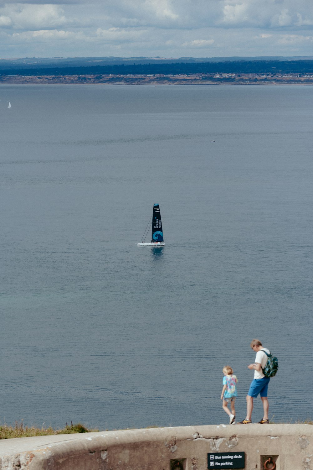 a man and a child are standing on a ledge looking out at the water