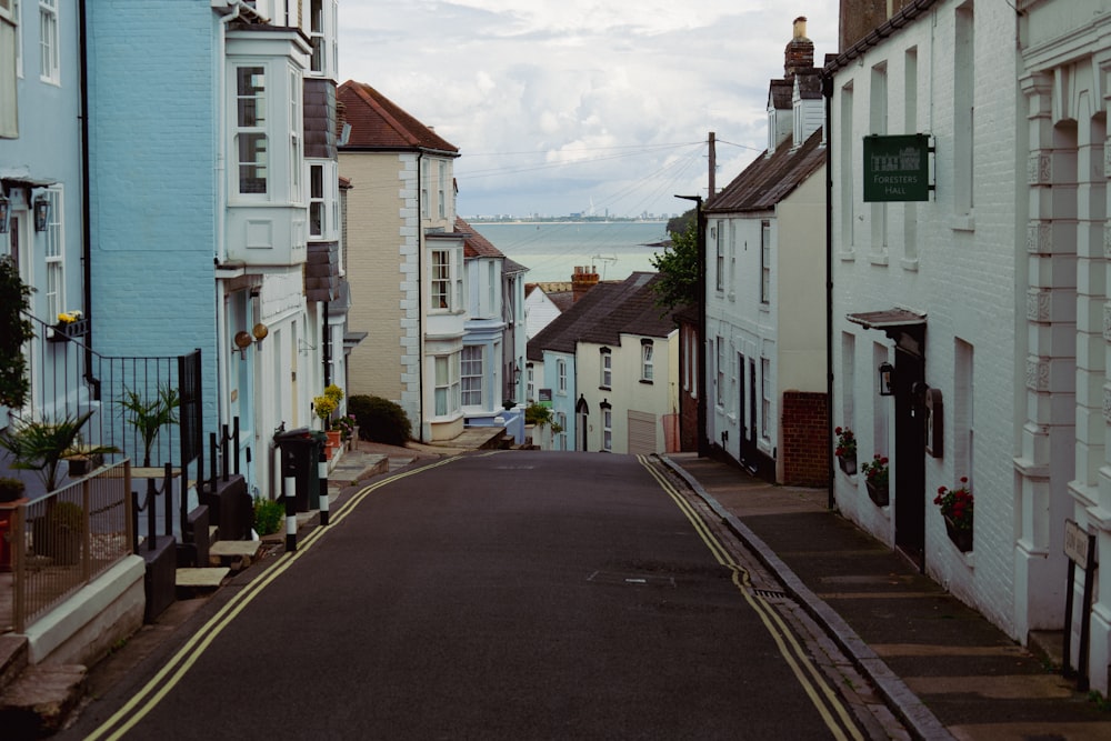 a narrow street lined with white buildings next to a body of water