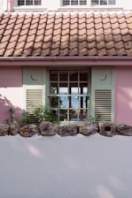 A charming seaside cottage with colorful shutters overlooking a tranquil beach.