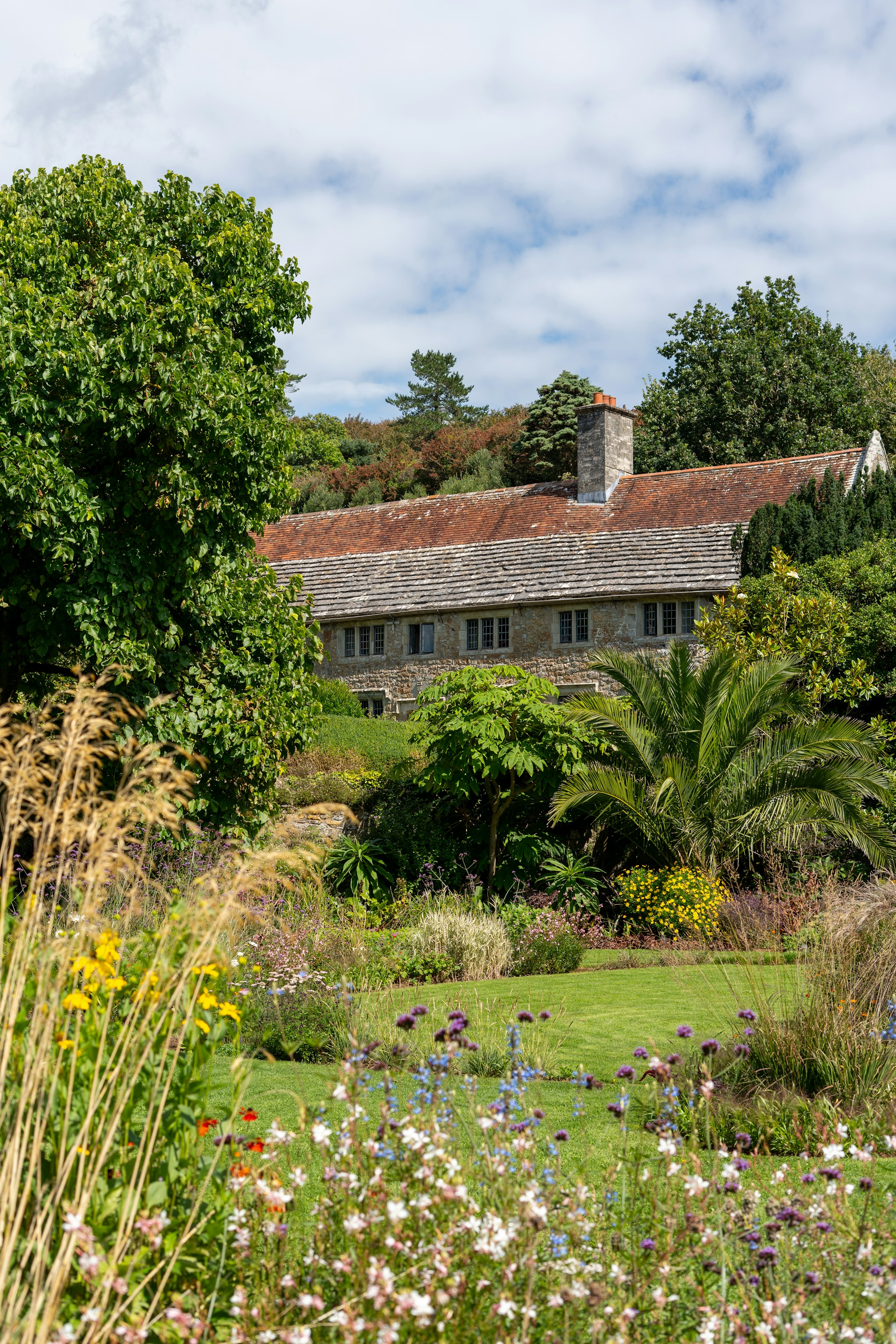 Sunny exterior view of the charming stone facade and lush garden surrounding the rural house.
