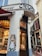 A corner bakery shop with a traditional facade featuring a painted mural of a woman holding bread. The entrance has wooden doors, and inside, there are displays of pastries and baked goods. The exterior is adorned with vintage-style lettering.
