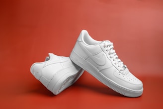 a pair of white nike sneakers on a red background