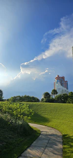 People walking in a park near a brown concrete building in Istanbul under a bright sky.