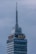 A tall skyscraper with an antenna at the top, featuring a digital clock displaying the same time on two sides. The building has several floors, with a section labeled 'LATINO SEGUROS'. The sky is overcast, giving a greyish backdrop.