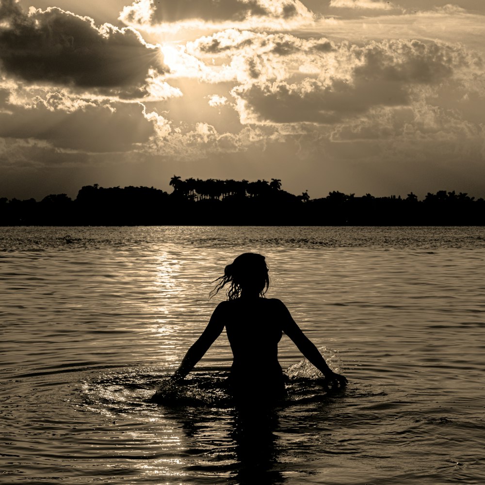 a woman in a body of water under a cloudy sky