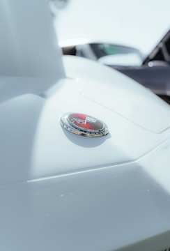 Close-up of a car hood emblem with a triangular logo and chrome accents. The image is focused on the shiny badge, emphasizing the sleek design and details.