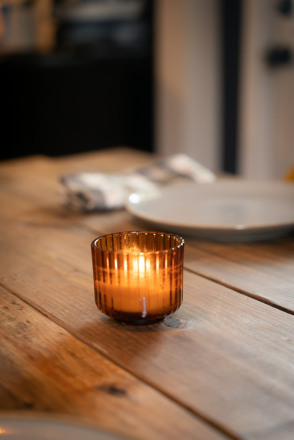 una candela accesa seduta sopra un tavolo di legno