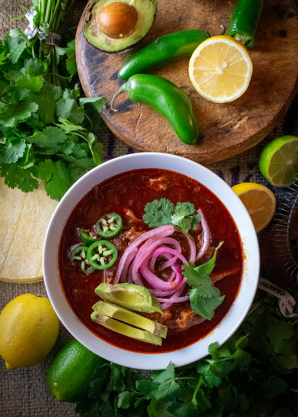 a bowl of soup on a table with limes, cilantro, and