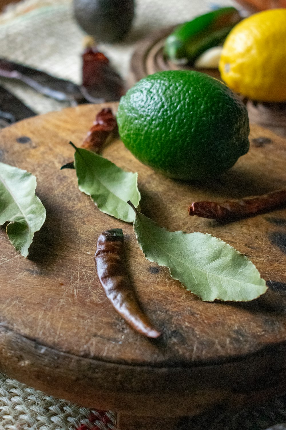 a wooden cutting board topped with green leaves and a lemon