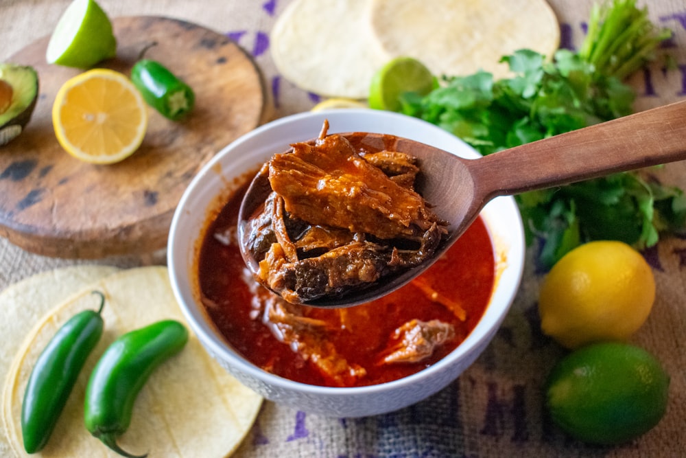 a spoon full of chili sauce with tortillas and limes in the background