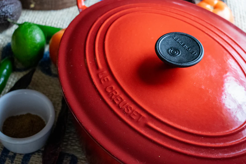 A covered Dutch oven ready for a braise, beside fresh ingredients