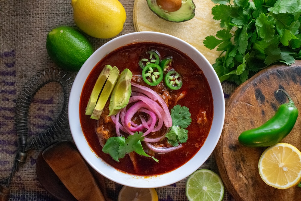 a bowl of chili soup with limes, cilantro, limes,