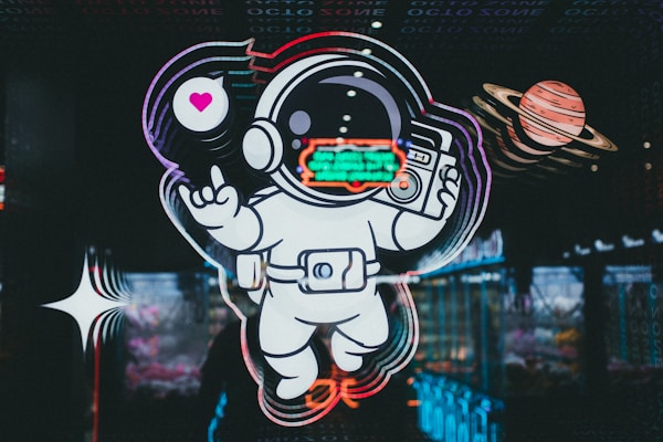 A neon-style illustration of an astronaut floating in space, holding a retro radio with a speech bubble displaying a heart. Beside the astronaut, there is a depiction of a planet with rings, resembling Saturn. The background features abstract, colorful reflections, enhancing the futuristic and psychedelic theme.
