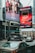 Large, vibrant billboards displaying advertisements and promotions are mounted on the sides of a tall building. Below, a busy urban street is filled with cars and pedestrians, indicating a bustling city atmosphere.