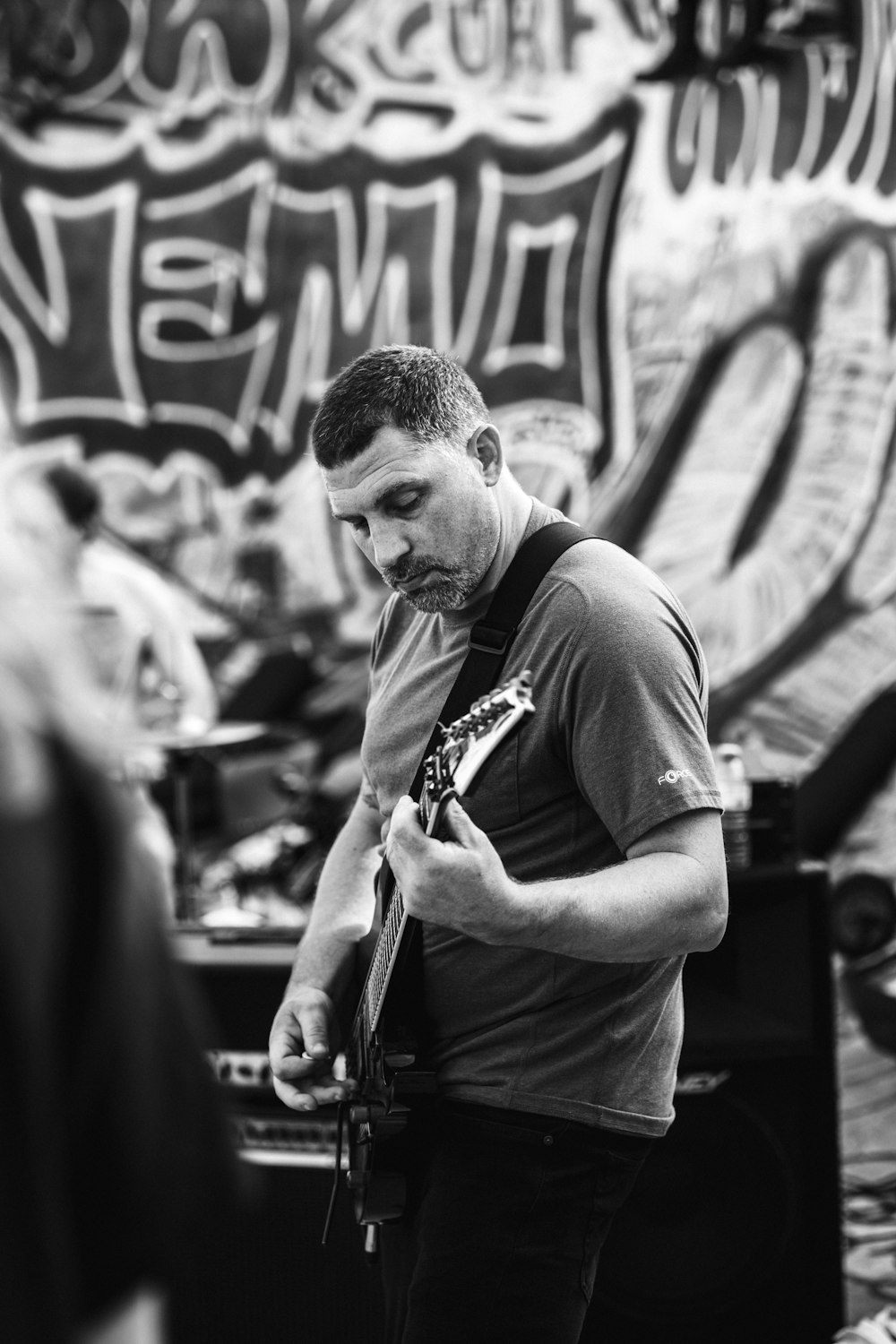 a man playing a guitar in front of a graffiti covered wall