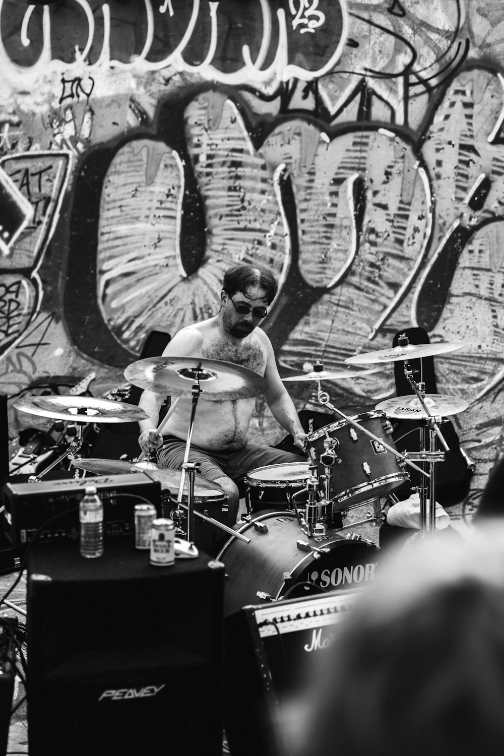 a man playing drums in front of a graffiti covered wall
