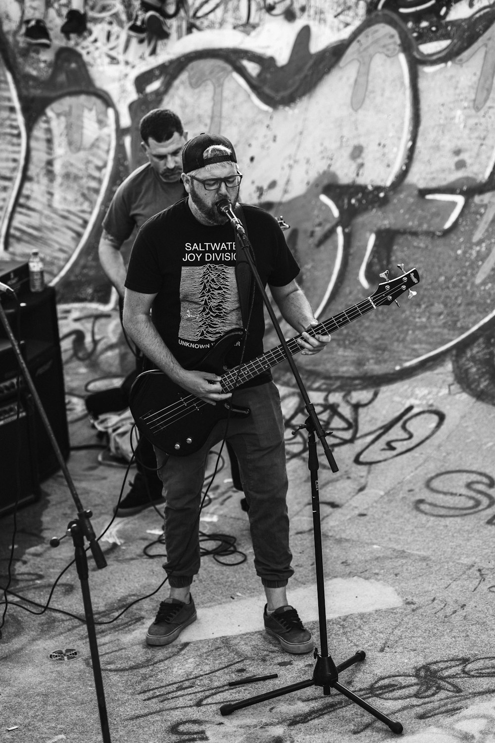 a man playing a guitar in front of a wall with graffiti