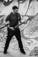 Guitarist shredding with aggressive stance against a backdrop of industrial metal scaffolding.
