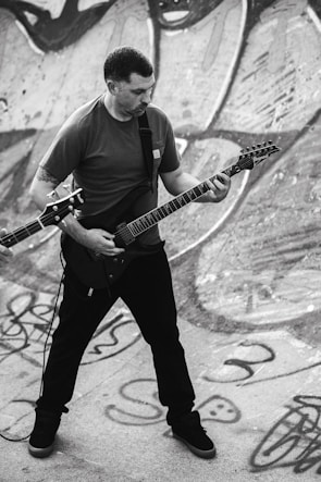 Guitarist shredding with aggressive stance against a backdrop of industrial metal scaffolding.