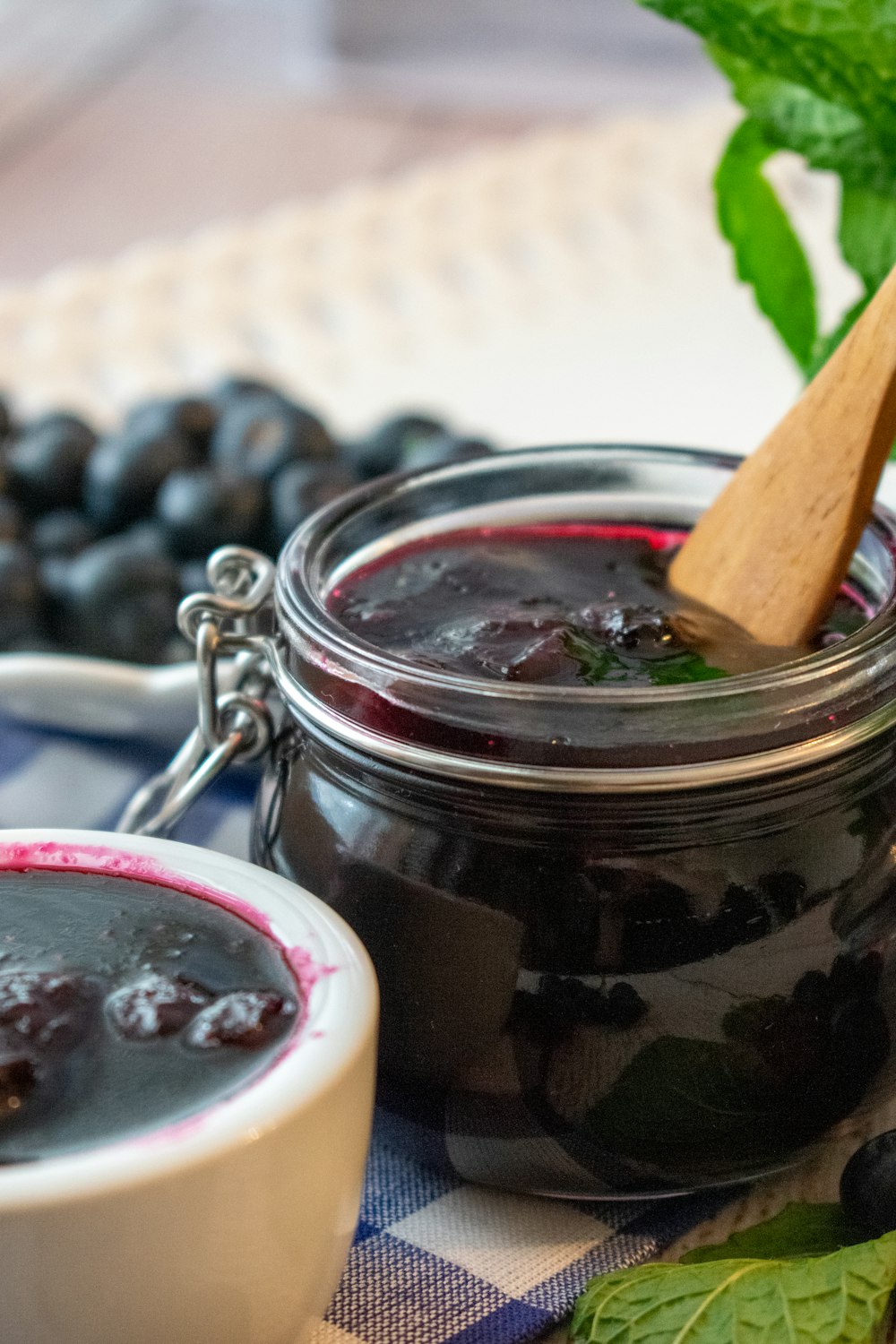 a jar of blueberry jam next to a bowl of blueberries