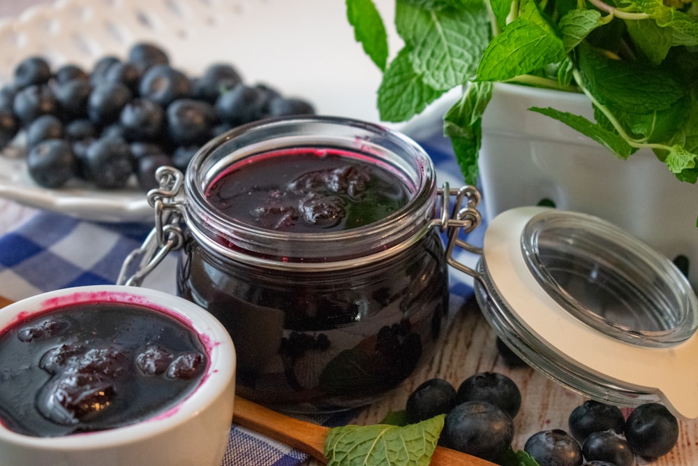 a jar of blueberry jam next to a bowl of blueberries