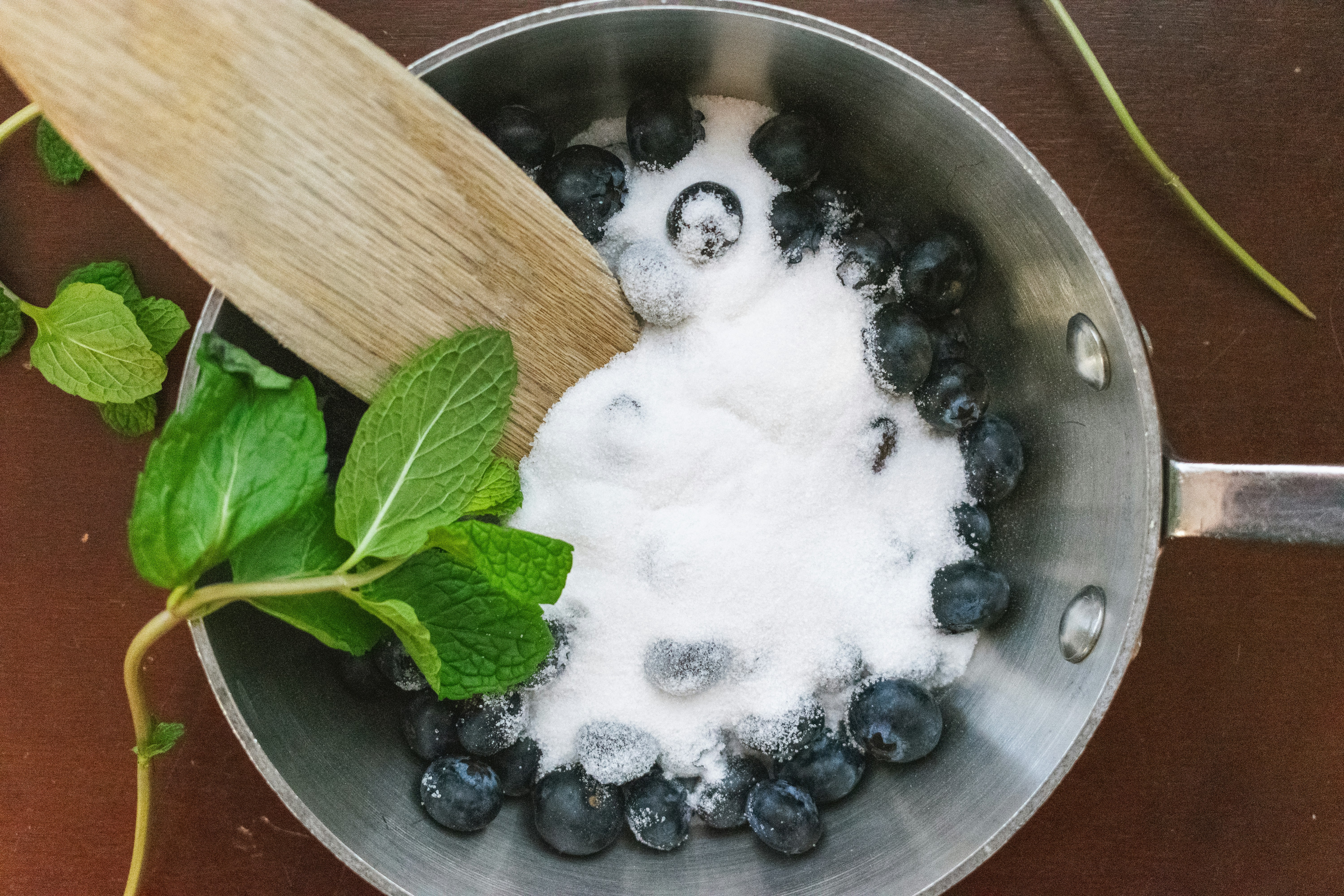Blueberries with sugar and mint in a saucepan