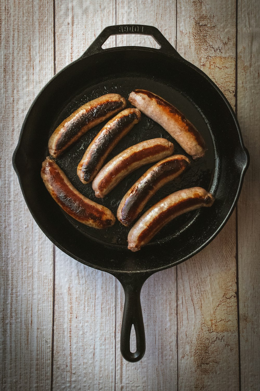 a cast iron skillet filled with sausages on a wooden table