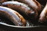 a group of hot dogs cooking in a frying pan