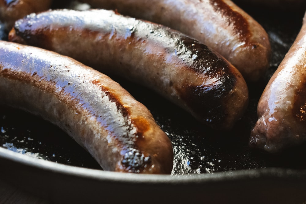 a group of hot dogs cooking in a frying pan