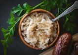 a wooden bowl filled with rice next to a spoon