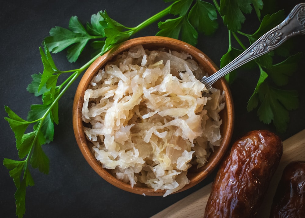 a wooden bowl filled with rice next to a spoon