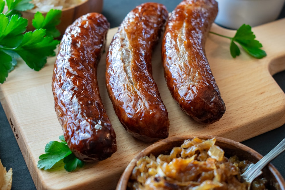 a wooden cutting board topped with four sausages