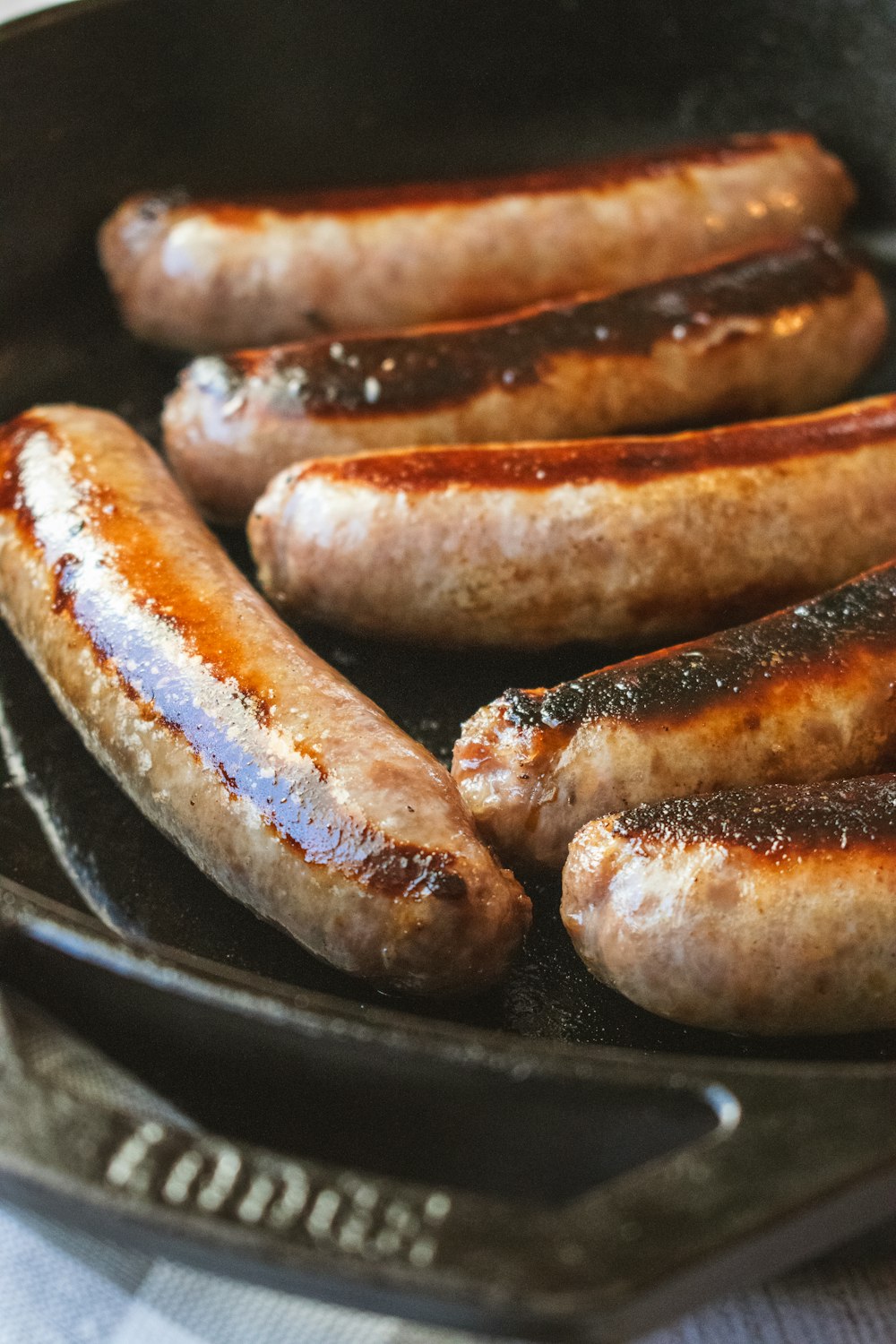 a group of sausages cooking in a frying pan