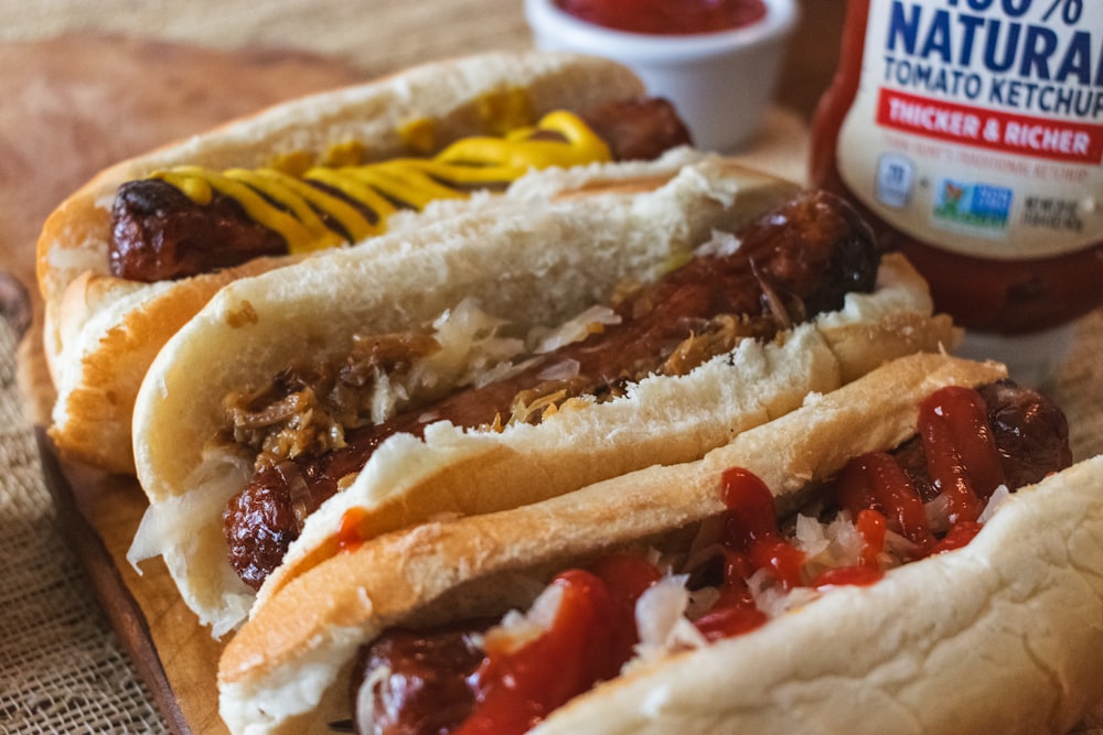 a couple of hot dogs sitting on top of a wooden cutting board