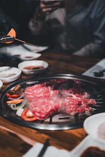 Chef carefully placing thin slices of beef on the grill, flames flickering beneath.