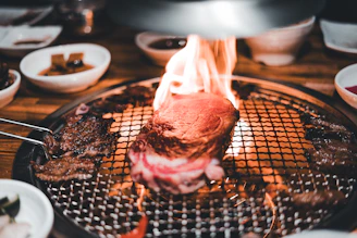 A lively grill with sizzling meats over open flames, surrounded by rustic wooden tables filled with happy diners.