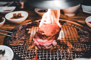 Grilled steak over an open fire pit, flames licking the edges, showcasing a traditional Patagonian asado.