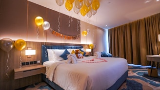 a bedroom with balloons and a bed with a teddy bear on it