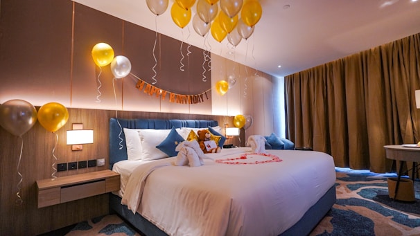 a bedroom with balloons and a bed with a teddy bear on it