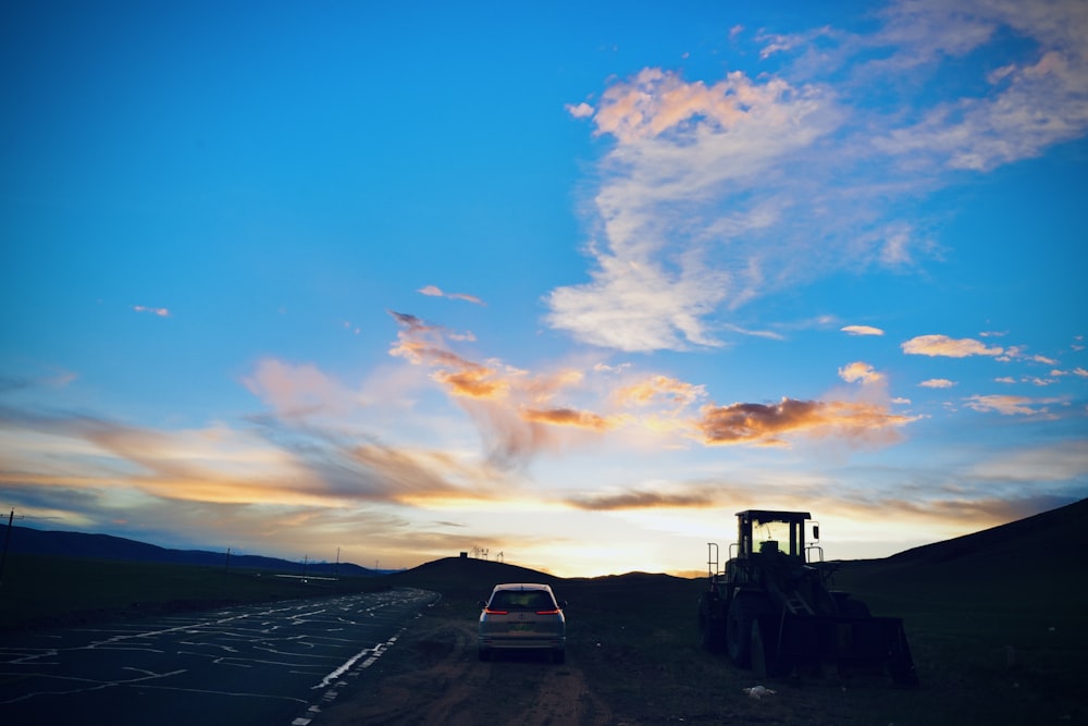 a car parked on the side of a road next to a tractor