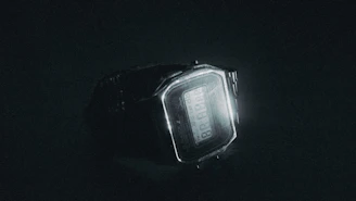 A stylish digital watch glowing softly against a dark background.