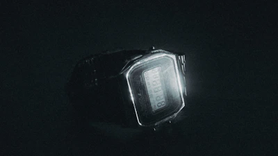 A stylish digital watch glowing softly against a dark background.