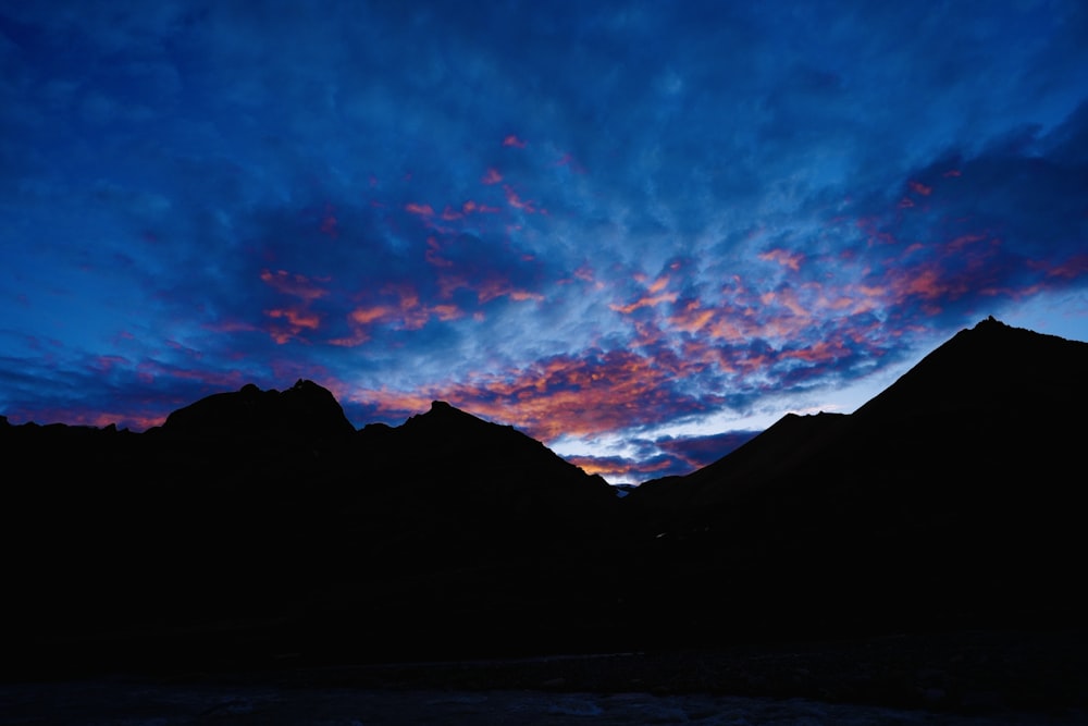 a mountain range is silhouetted against a blue sky