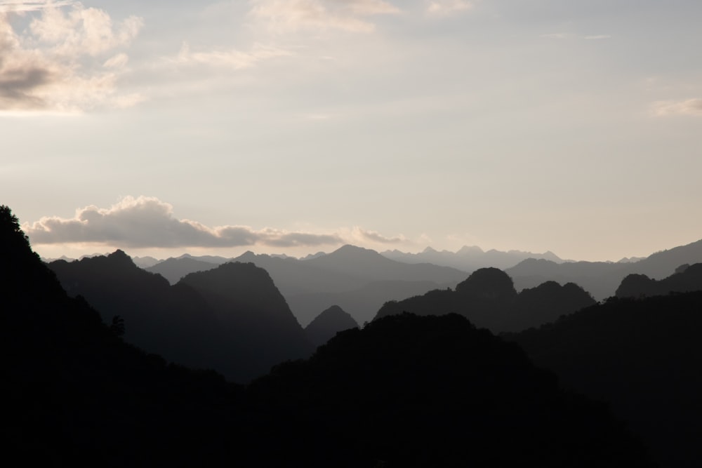 the silhouette of a mountain range against a cloudy sky