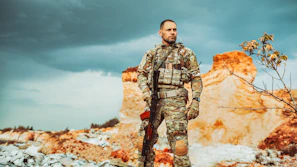 A lone survivor wearing military-style gear, standing watch in a misty post-apocalyptic landscape.
