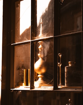 A warm sunlit studio corner featuring an array of vintage candlestick mullers and wool skeins arranged like sacred relics.
