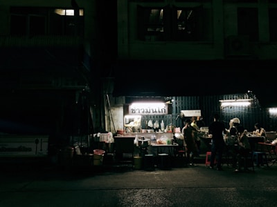 Evening scene with warm lights illuminating a food stall bustling with people enjoying their meals.